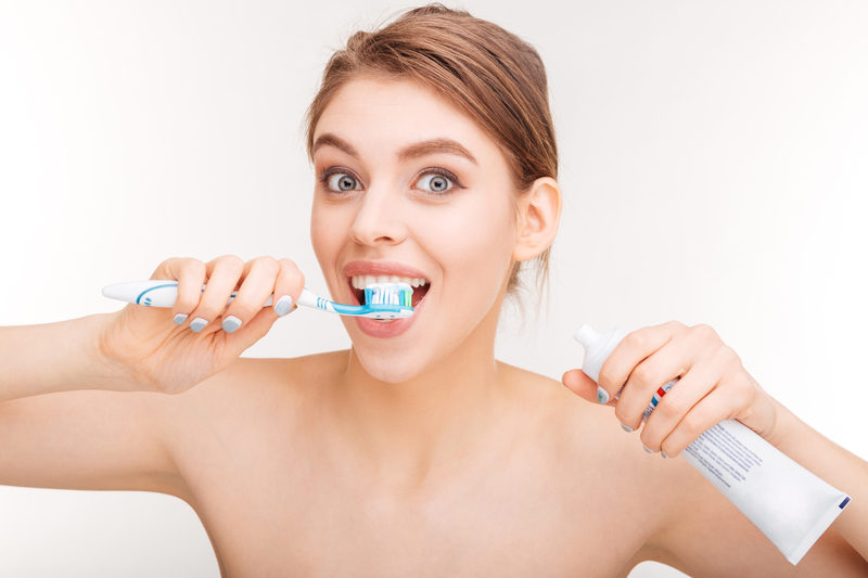 A woman brushing her teeth with a blue tooth brush A woman brushing her teeth with a blue tooth brush
