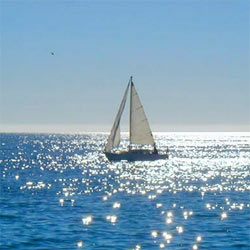 A small sailing yacht sailing across a sparkling sea