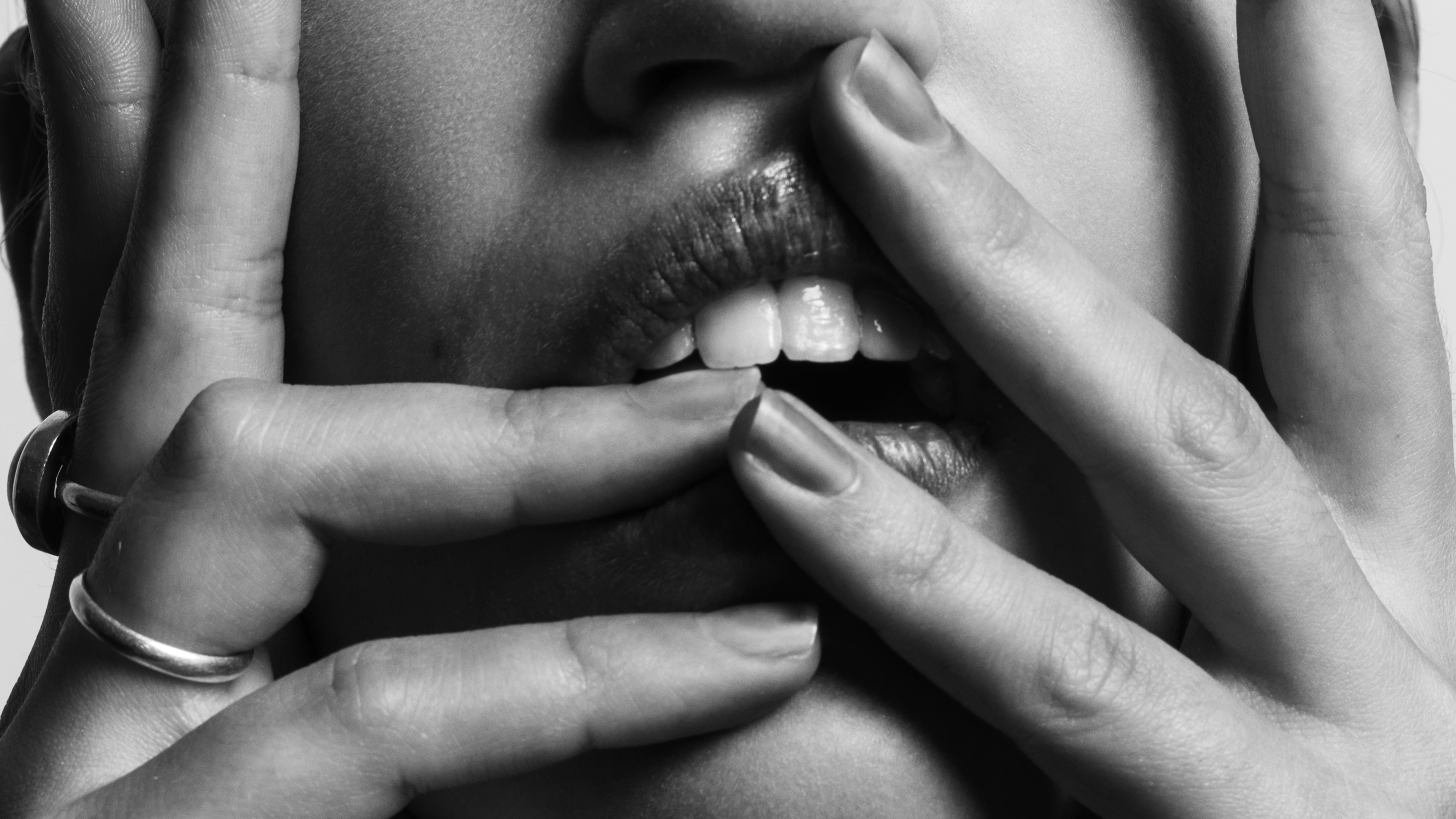A woman holding her fingers over her mouth, with her teeth showing. A woman holding her fingers over her mouth, with her teeth showing.