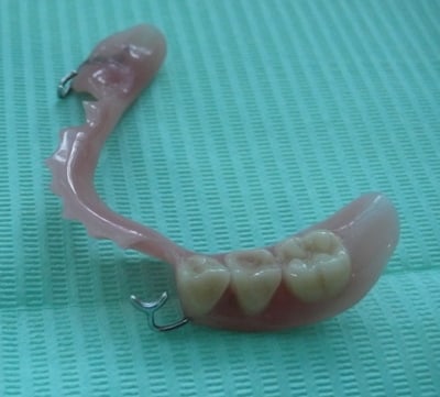 A lower partial denture in acrylic on a green background