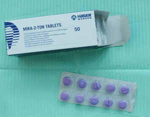 A packet of disclosing tablets on a green background