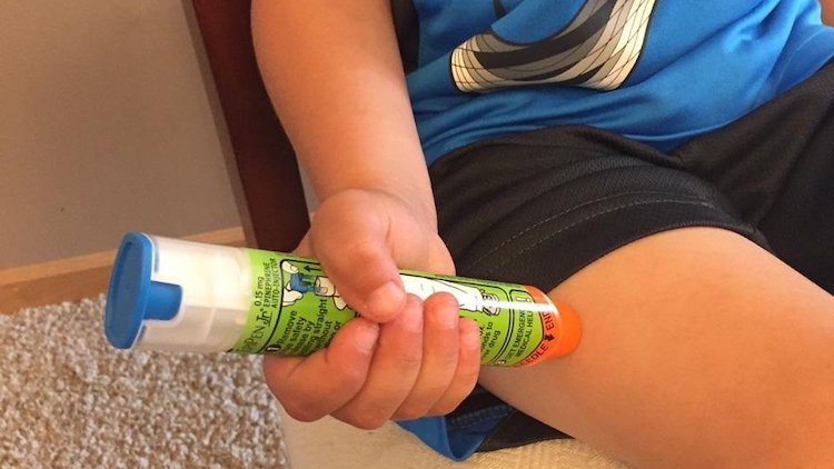 An EpiPen being held against a teenager's leg An EpiPen being held against a teenager's leg