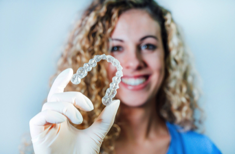 A dental nurse in a blue top holding an Invisalign splint A dental nurse in a blue top holding an Invisalign splint