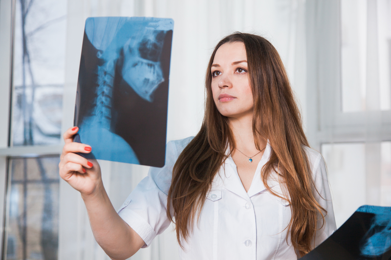 A lady in a white coat holding a large X-ray film.