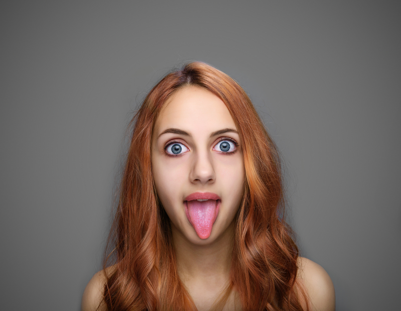 A young woman with big eyes and red hair sticking her tongue out at the camera. A young woman with big eyes and red hair sticking her tongue out at the camera.