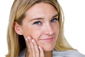 A woman with blond hair holding her right hand to her right cheek, looking at the camera