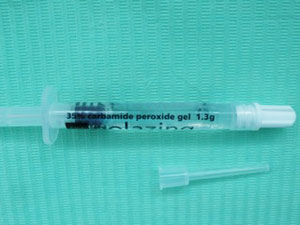 A clear plastic syringe containing tooth whiten gel, against a green background. A clear plastic syringe containing tooth whiten gel, against a green background.
