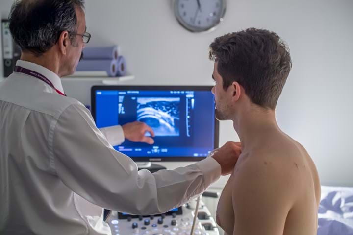 A doctor using an ultrasound scanner to check a mans neck
